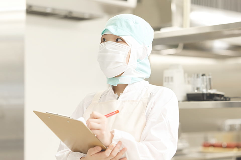 割烹姿でメモ書きをする女性