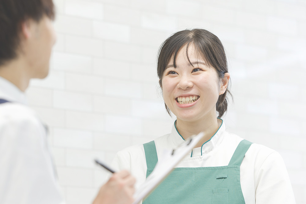 エプロン姿の女性が笑顔で同僚と話している姿