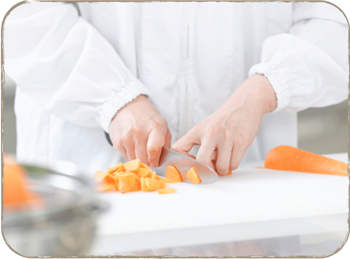 人がまな板の上で人参を切っている様子。