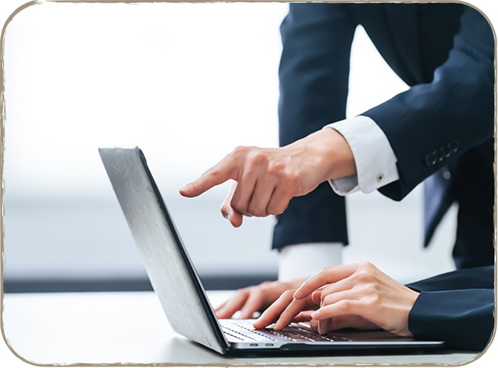 ビジネスマンがノートパソコンを指差している写真。