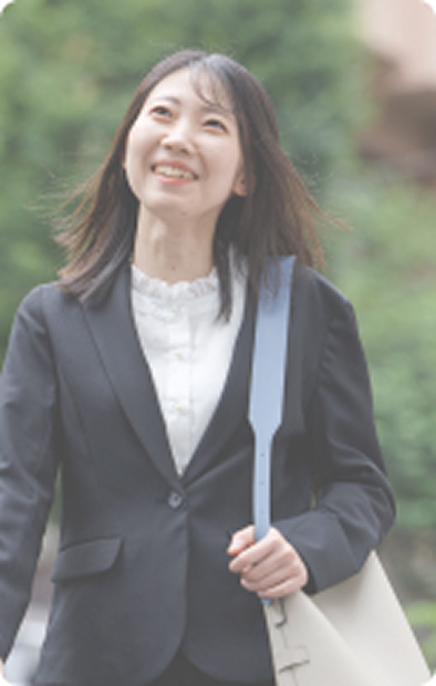 バッグを持ったビジネススーツ姿の女性が立っています。