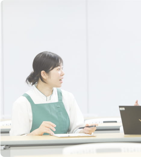 教室で話し合う二人の女性が向かい合っている様子。