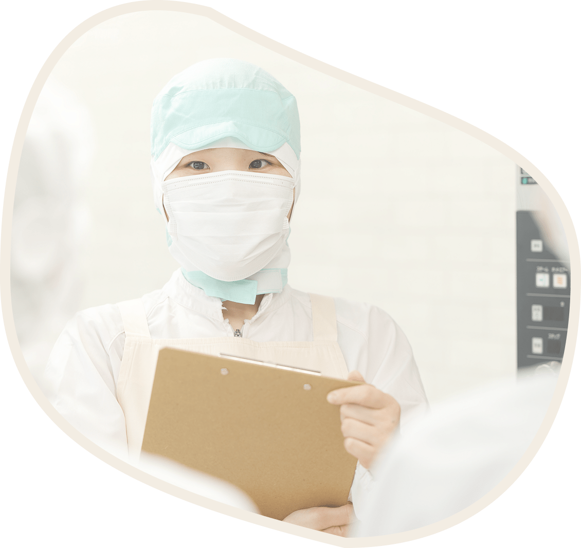 クリップボードを持ち、マスクを着用した女性の写真です。