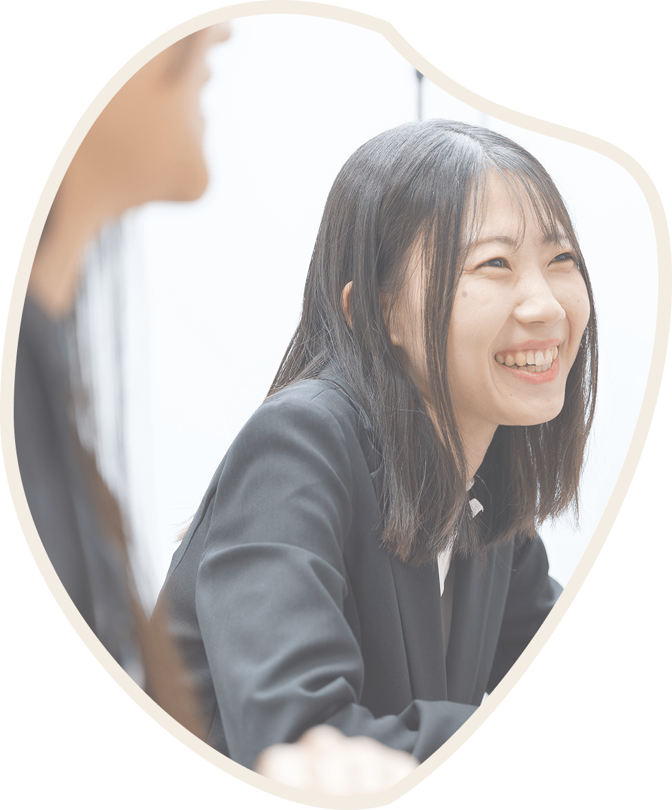 テーブルに座るビジネススーツの女性が笑顔を見せている。